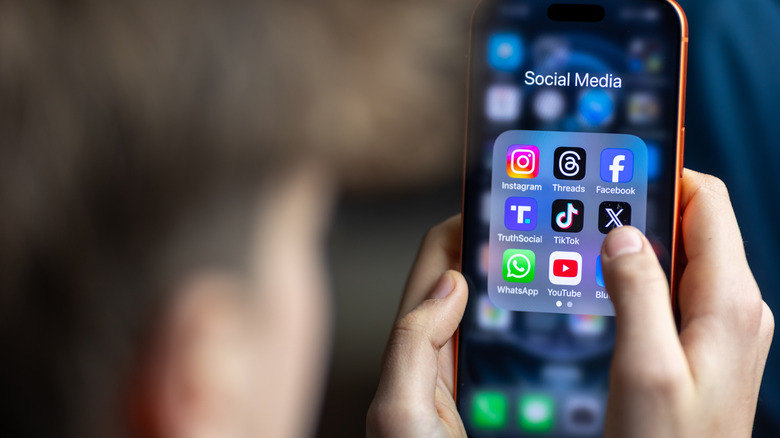 Teen holds iPhone with various social media app icons on display