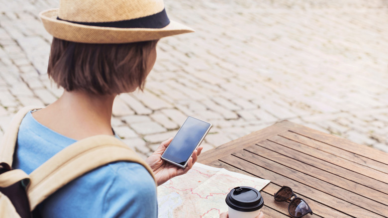 A woman traveler using phone while having coffee