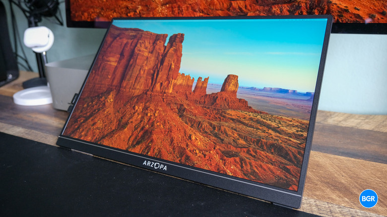 An Arzopa Z1RC portable monitor showing a rugged desert cliff landscape.