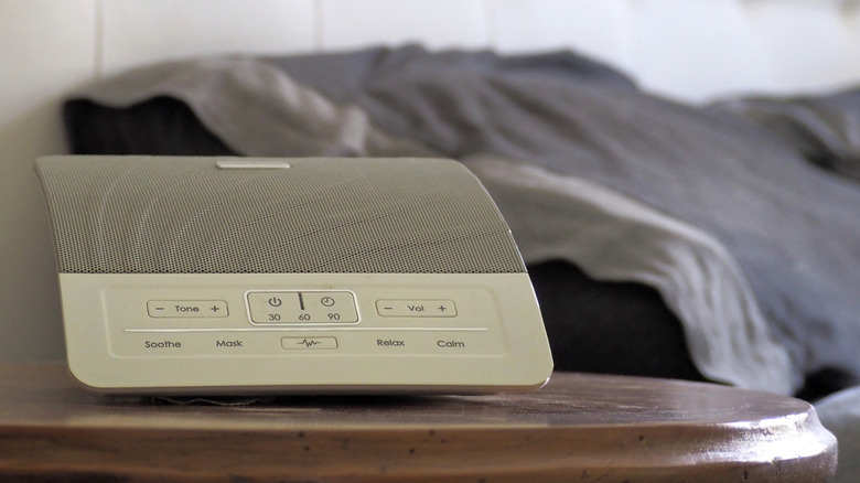 A white noise machine next to a bed