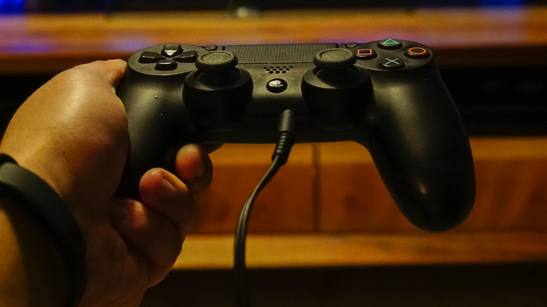 Someone holding using a controller on the PS4