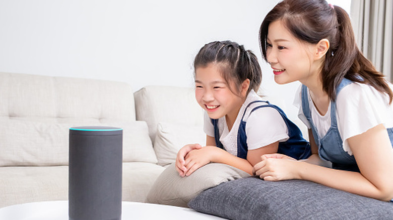 Mum and daughter talking to a voice assistant at home
