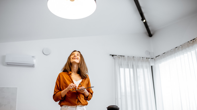 Woman controlling a smart home ceiling light as she looks up directly at it