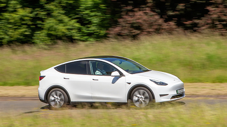 White Tesla Model Y driving on a country road