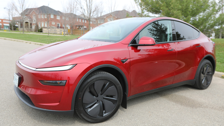 The side view of a red Tesla Model Y parked on a street