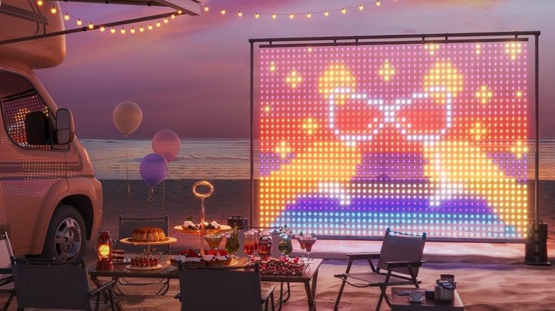 The Govee Lightwall set up on a beach during sunset showing a large image of cocktail glasses clinking.