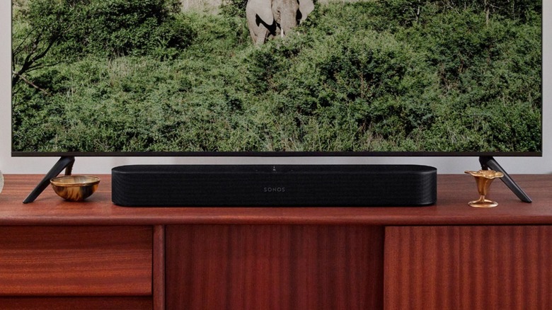 The Sonos Beam (Gen 2) soundbar on a wooden surface, in front of a TV.