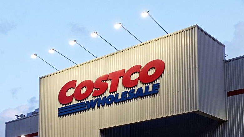 The Costco logo on the facade of a building, illuminated by floodlights.