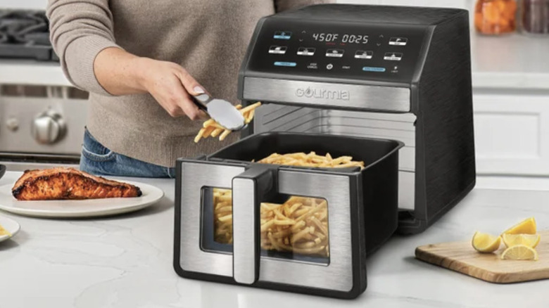 A woman making french fries in the Gourmia 8-Quart Digital Air Fryer