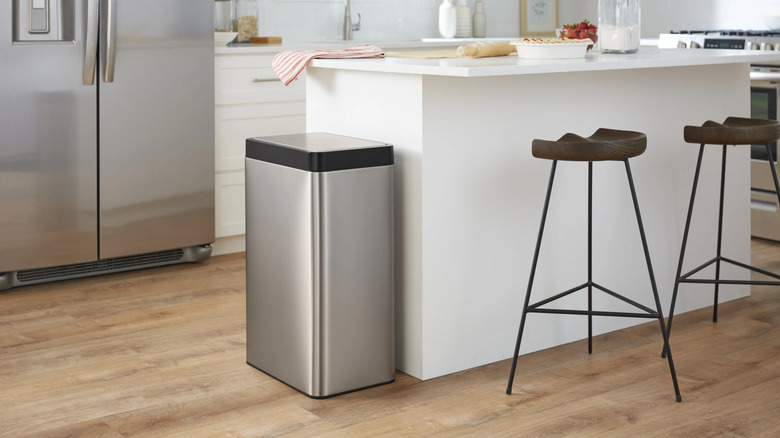 Kohler 48-liter stainless steel motion sensor trash can beside a kitchen island.