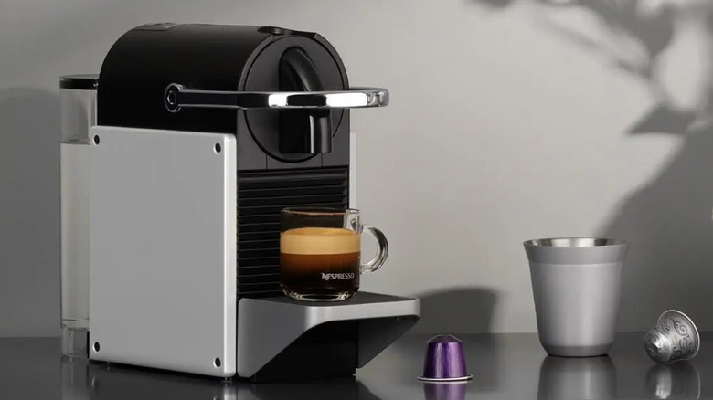 Nespresso Pixie Espresso Machine by De'Longhi brewing a shot on a kitchen table.