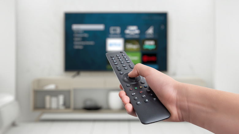 A person pointing a remote at a smart TV.