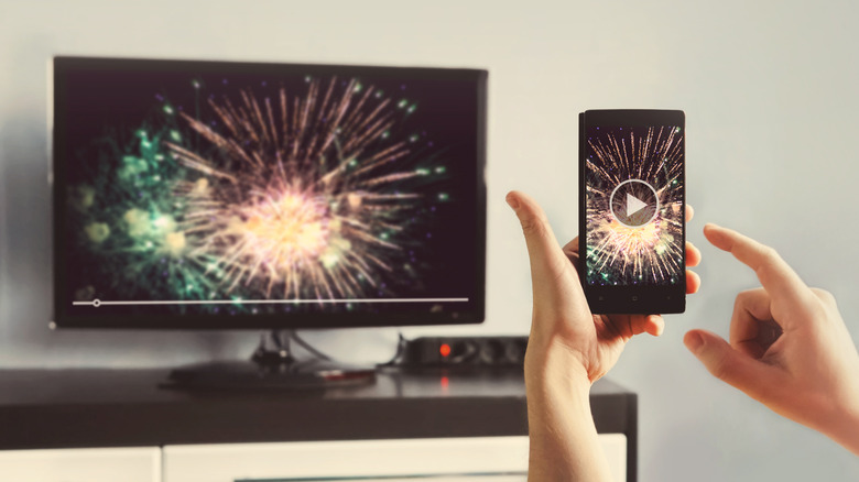 A person mirroring the screen of their smartphone to their TV.