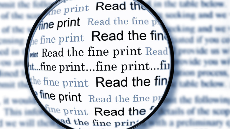 A magnifying glass over paper shows read the fine print at its center.