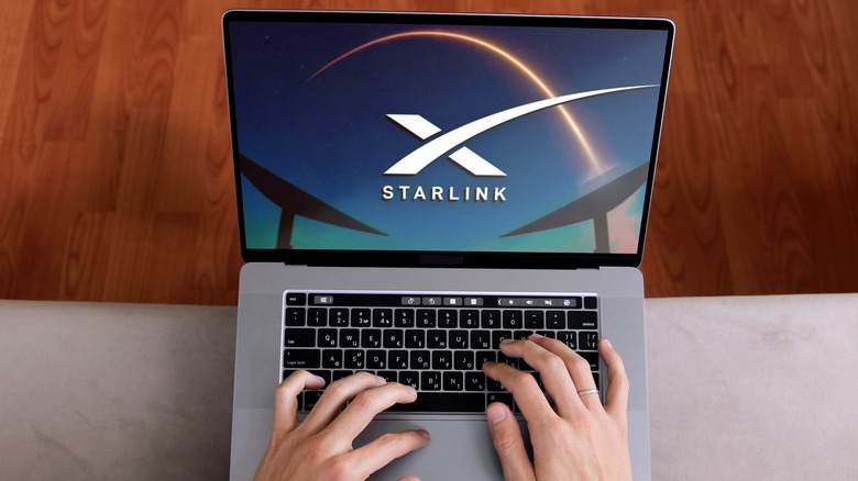Hands typing on a laptop keyboard with the Starlink logo on the screen.