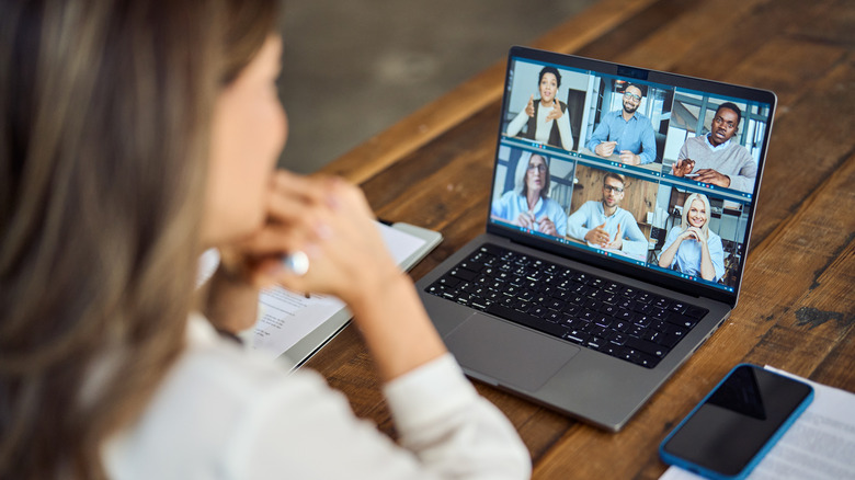 A woman sits in front of a laptop during a conference video call.