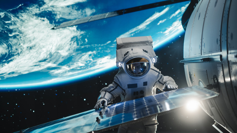 An astronaut performs maintenance on a satellite.