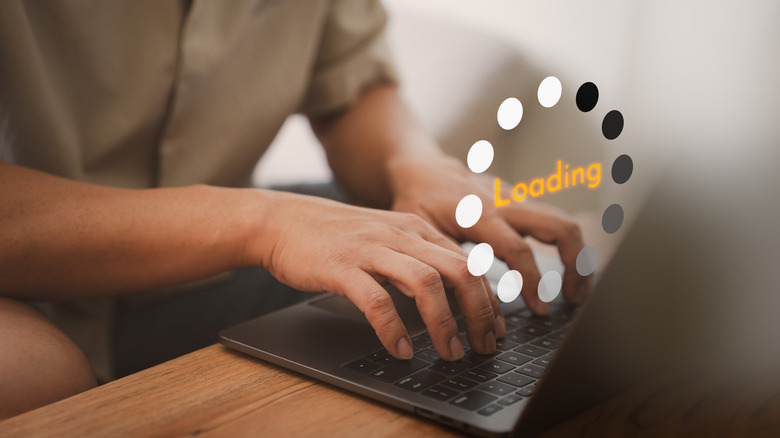 A person types on a laptop with a floating loading graphics above it.