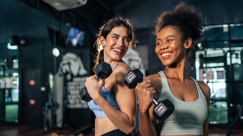 Two women lifting dumbbells in the gym.