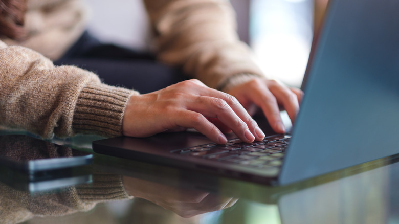 A pair of hands typing on a laptop keyboard.