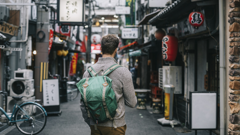 A tourist with a backpack on a city street or sidewalk.