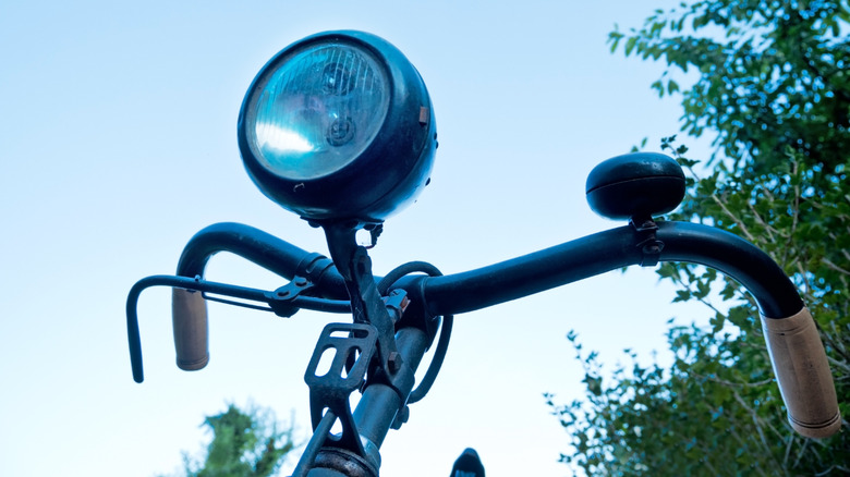 An old-fashioned bicycle light mounted on a retro bike's handlebars.