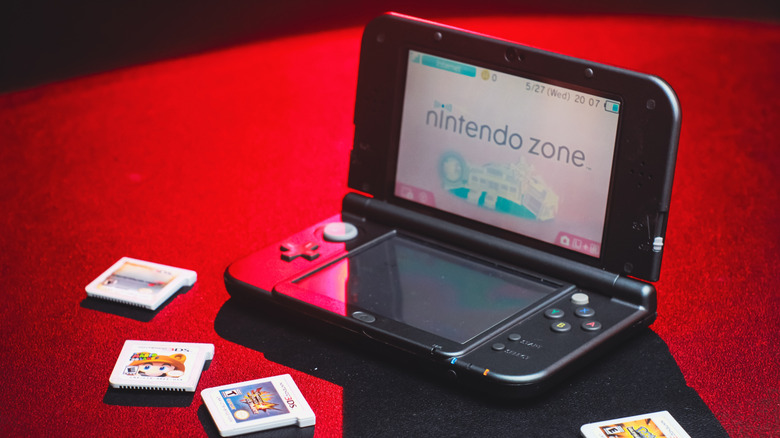 A Nintendo 3DS console surrounded by game carts and a stylus.