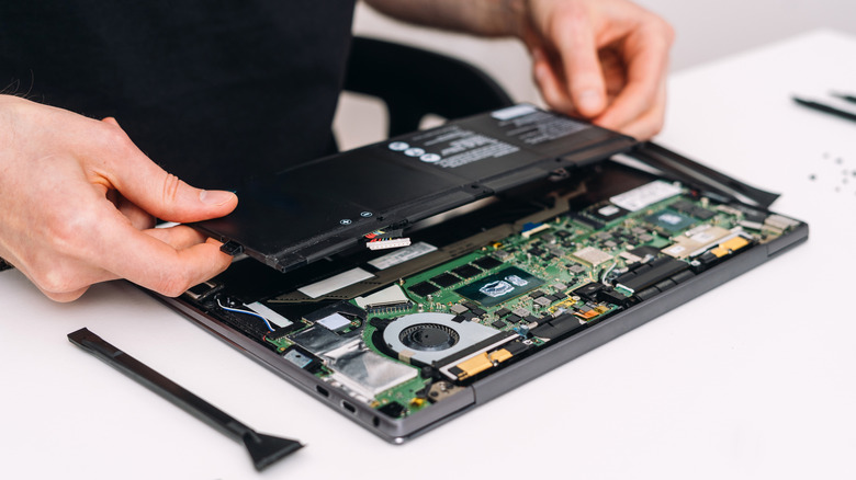 A person installs a replacement laptop battery.