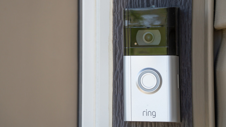 A ring video doorbell  mounted on the wood frame of a door.