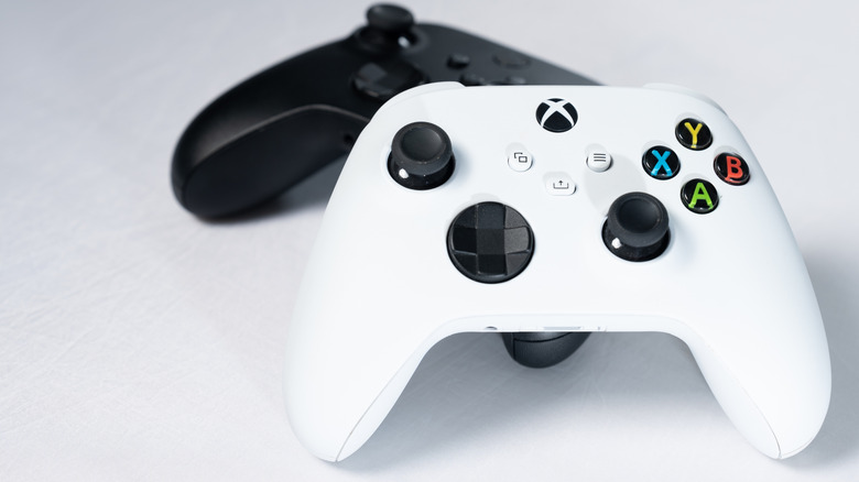 Two Xbox Series controllers on a gray surface.
