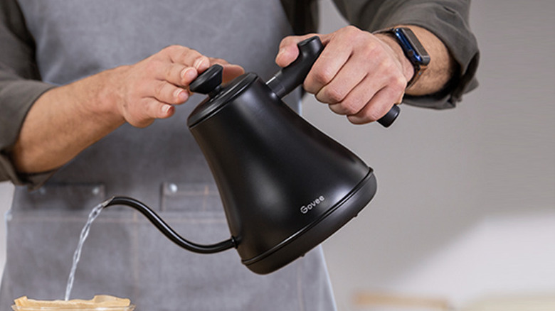 A man pouring water from a black kettle