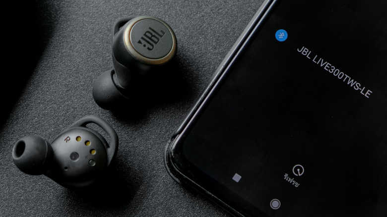 JBL Tune earbuds on a table connecting to a JBL app on an Android.