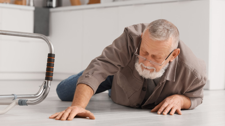 A senior fallen on the kitchen floor with his walker beside him