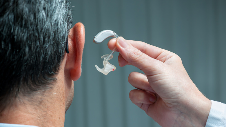 A doctor inserting a hearing aid in a man's ear