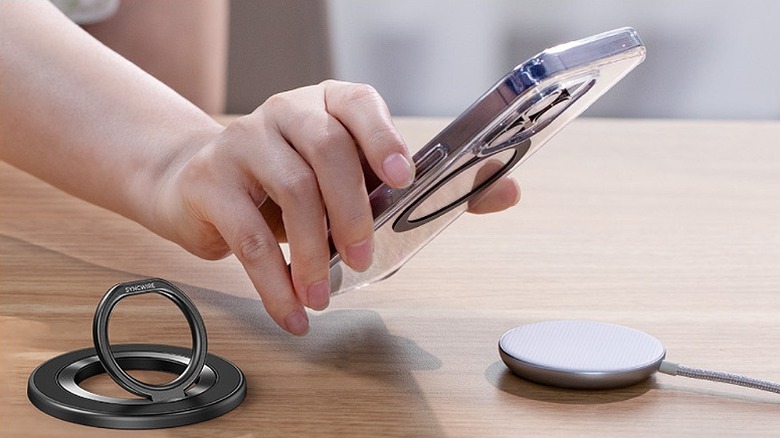 An iPhone placed above a MagSafe charger with a ring on the side.