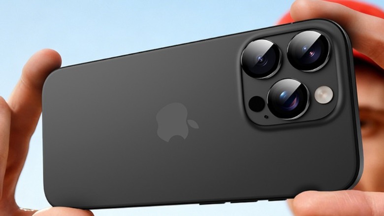 Boy holding a black iPhone 16 Pro horizontally.