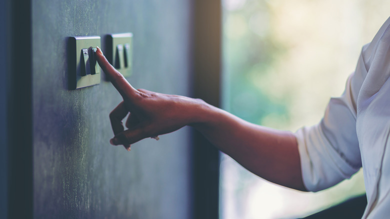 Woman pressing light switch on wall