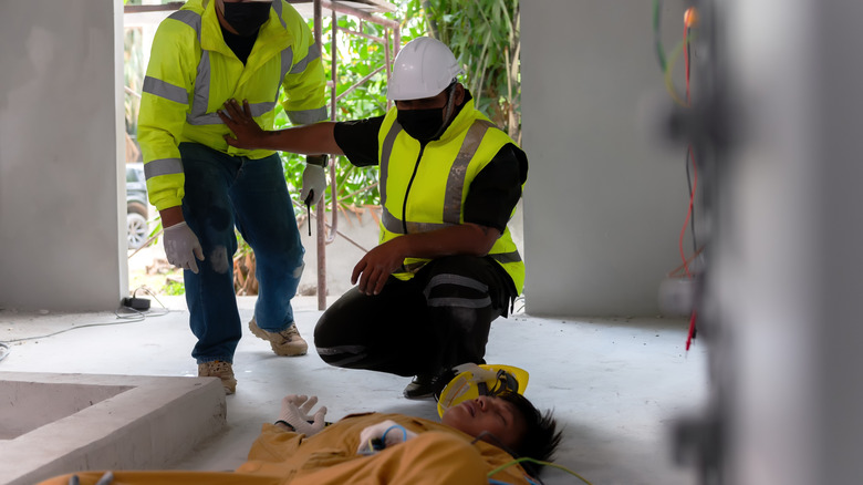 Workers looking at person lying unconscious