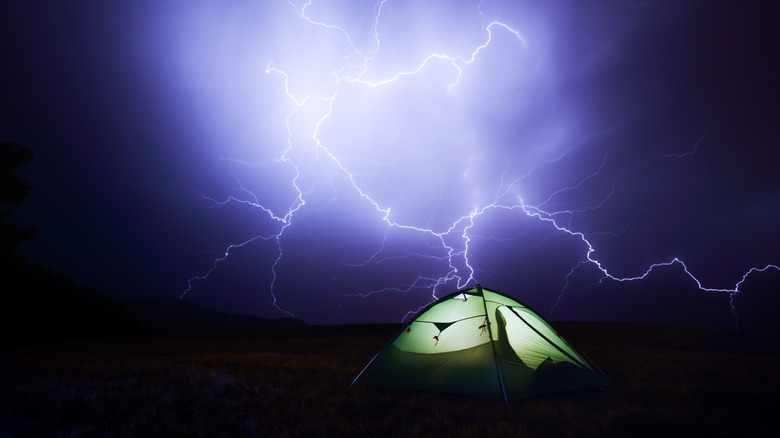 Green tent with lightning in the background