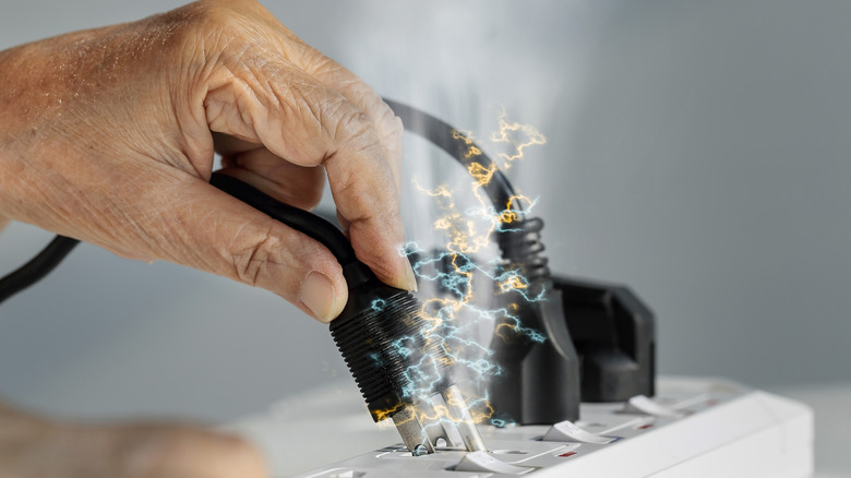 Elderly hand holding electrical plug