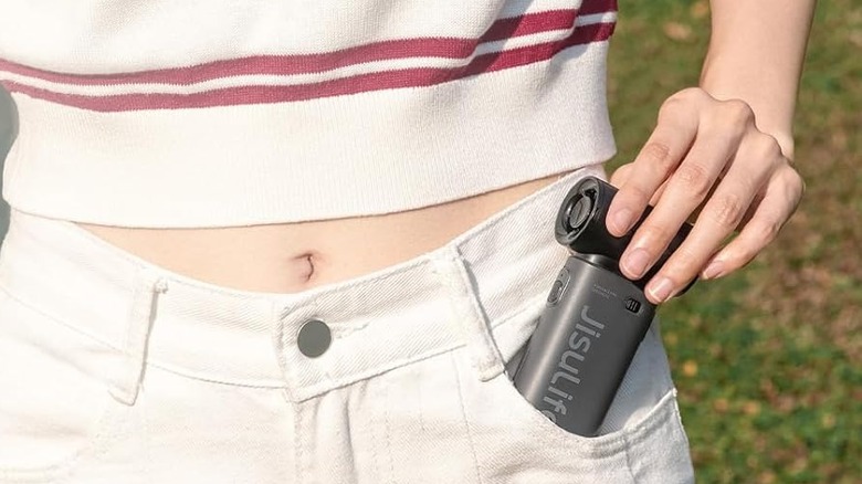 A person placing the Jisulife Life9 handheld fan in their pocket.