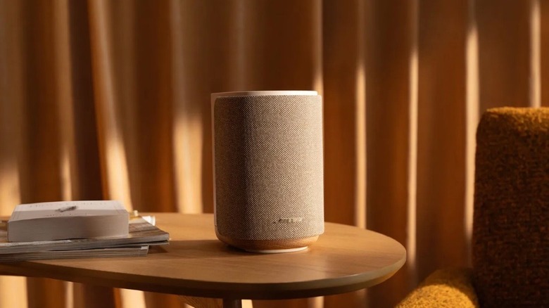 The Bose Lifestyle Ultra Speaker on a wooden table, beside a sofa.