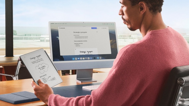 A man using the reMarkable Paper Pure digital notebook with a computer.