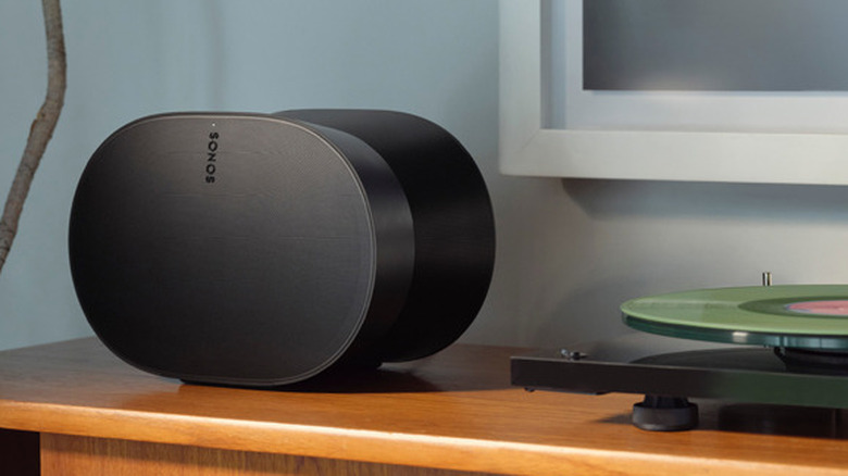 The Sonos Era 300 smart speaker beside a turntable on a wooden desk.