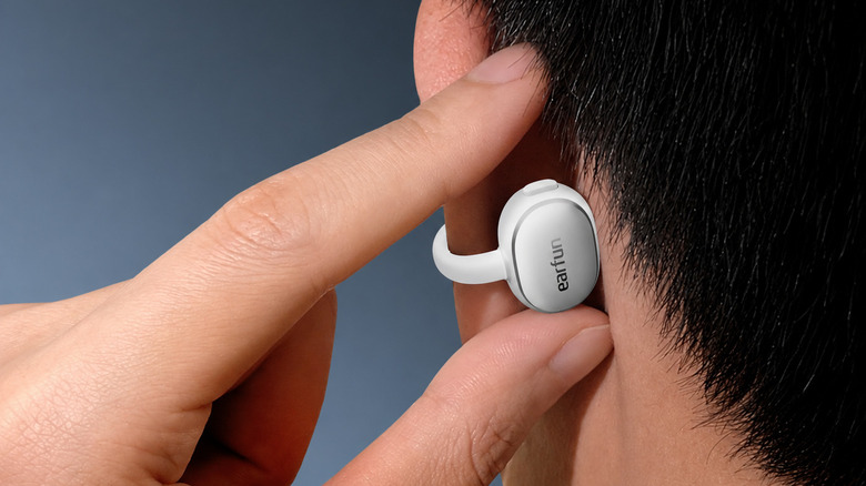 Man controlling white earfun clip 2 earbud on his left ear