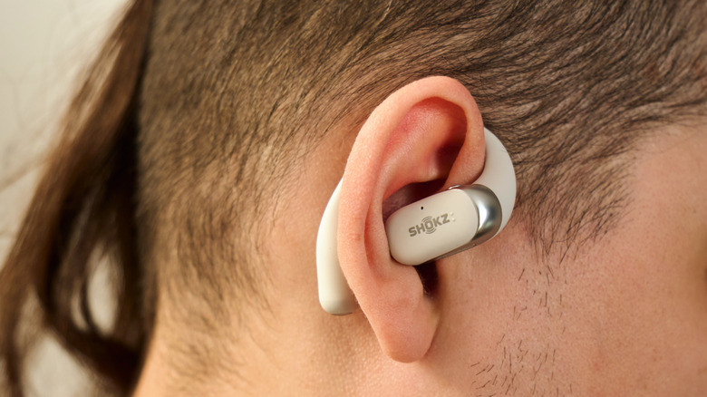 A man wearing white Shokz open-ear earbuds