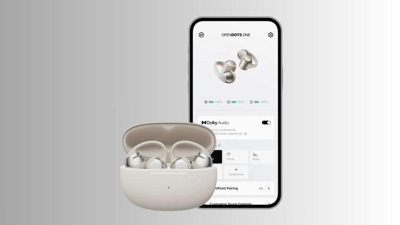 A pair of white Shokz opendots one in open case next to a smartphone with the shokz app