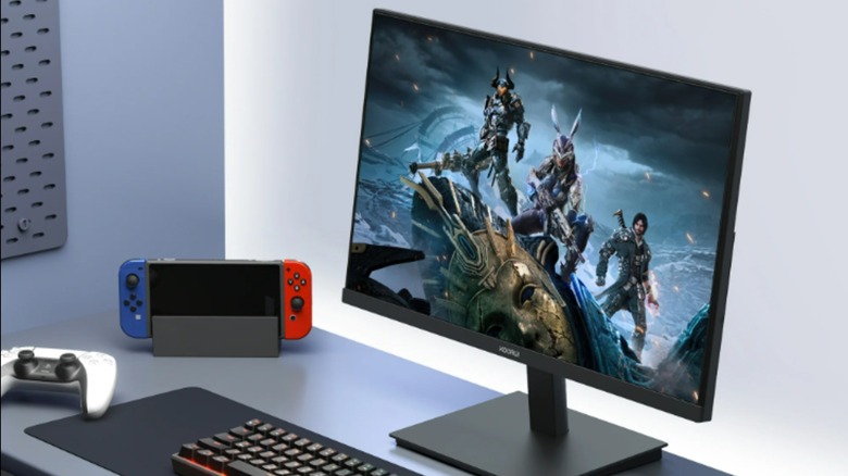 The KOORUI 24 Gaming Monitor on a desk along with a PS5 controller and Nintendo Switch