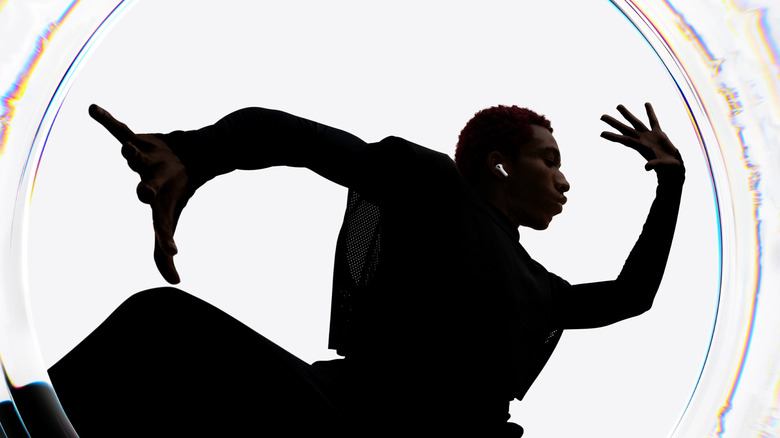A person in silhouette strikes a pose with Apple AirPods visible in their ears.
