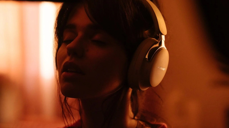A woman has her eyes closed as she listens to music on a set of Bose headphones.